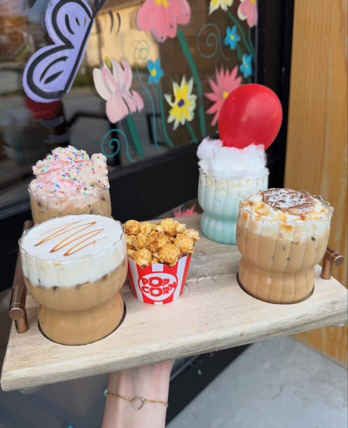 A four drink coffee flight from a Pittsburgh coffee shop with four different designed lattes on a wood tray themed to a carnival.