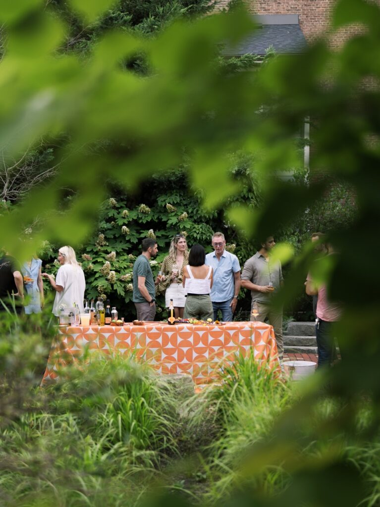 A group of people stand behind a table shot through an opening in the trees.