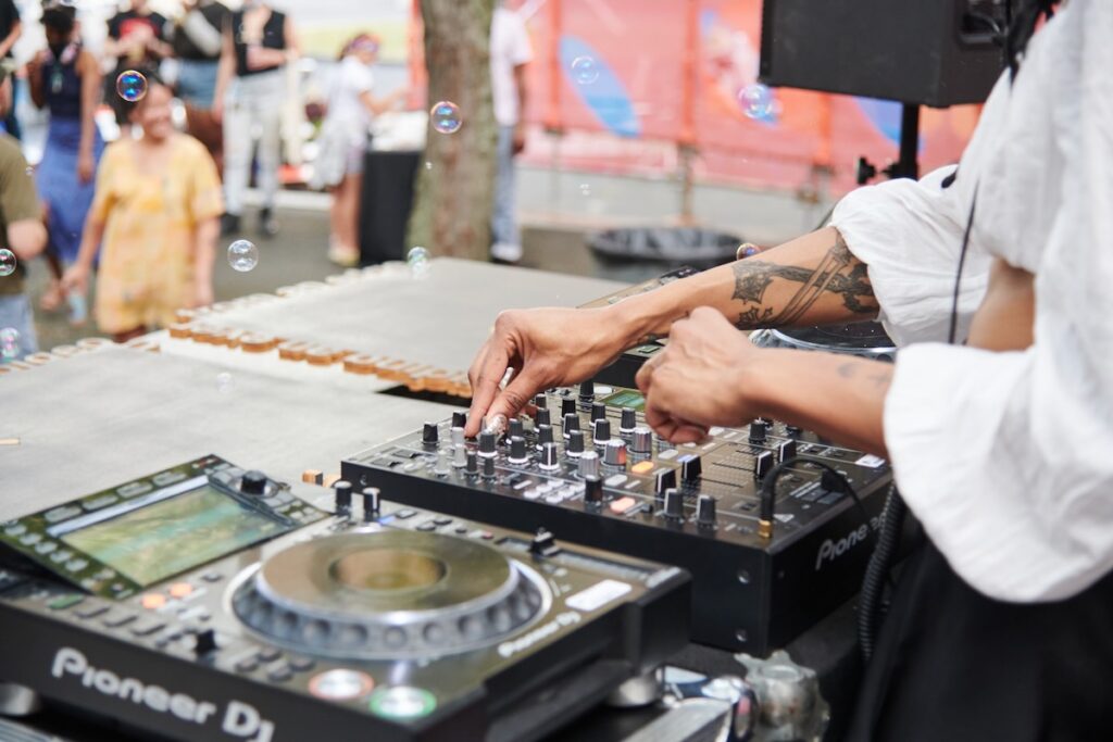 A person in a white shirt DJs at a party outside in Pittsburgh.