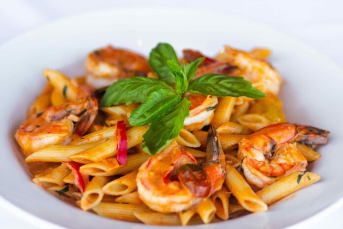 Monterey Bay Serves up Specialty Cocktails and Fresh Seafood to Match A white dish with pasta and shrimp with a red sauce garnished with green basil