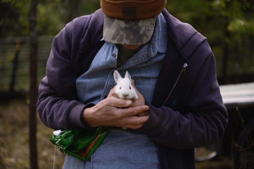 A man holds a tiny white bunny in his hands.