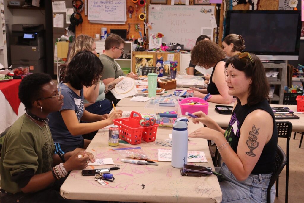 A group of people at a table in Pittsburgh make shrinkydinks at a craft event.