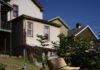 Sol Patch Garden is Braddock’s Home for Flowers A woman in a sun hat carries bright red flowers outside a house.