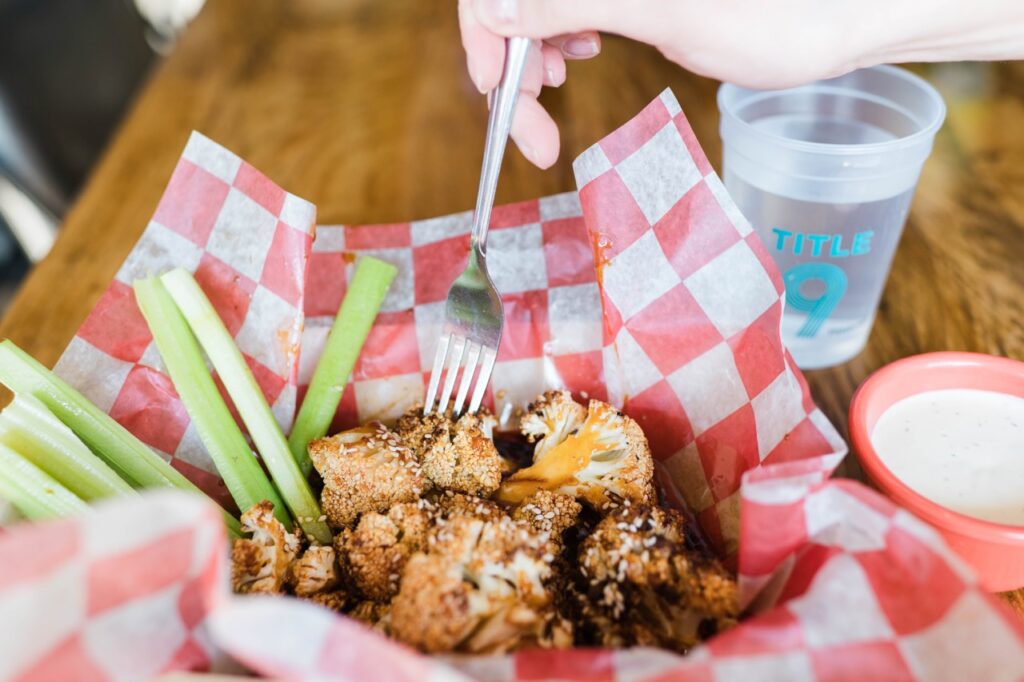 A person pokes with a fork at boneless wings in a basket.