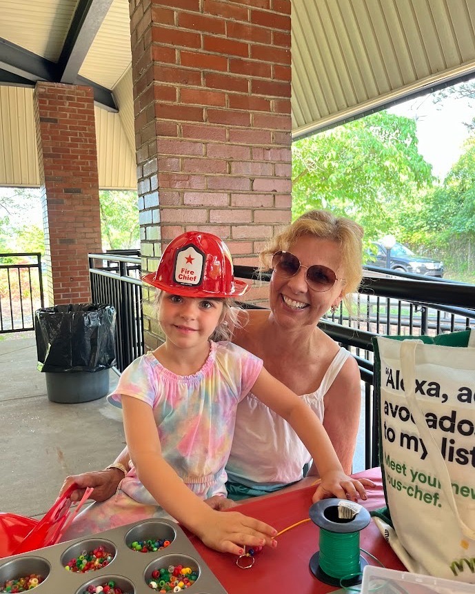 A mom and daughter sit together at a summer block party at a Pittsburgh library.