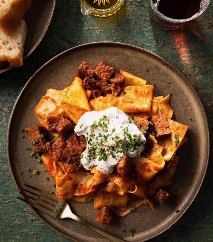 A brown plate holds a pasta and meat dish with ricotta on top from a top Italian restaurant in Pittsburgh.