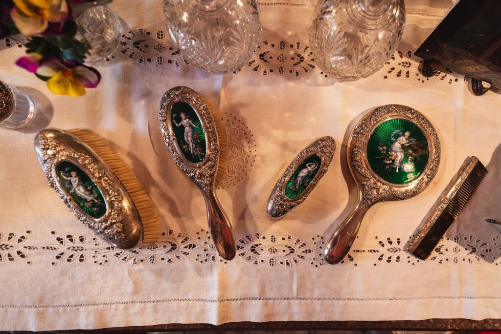 A set of four Gilded Age brushes on a white tabecloth.