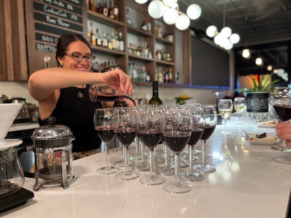 A bartender at Orbis Caffe pours a glass of wine.