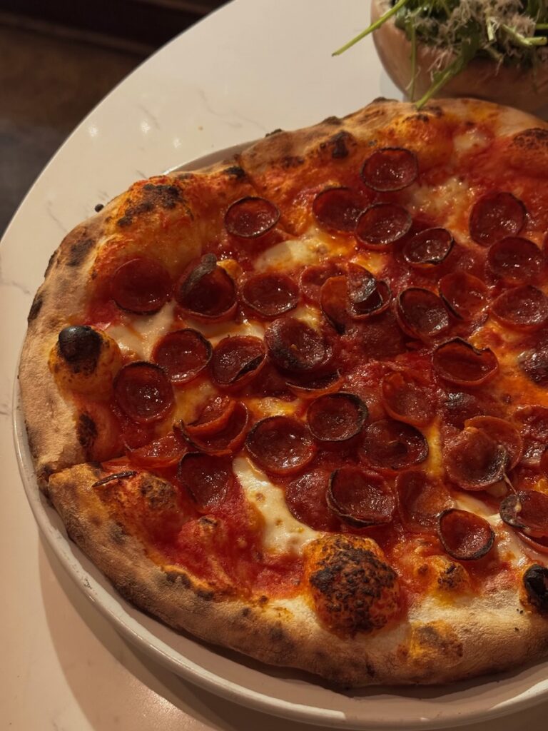 A Pittsburgh pizza sits on a white table with pepperoni on it. 