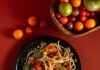 8 Pasta Recipes to Avoid the Grocery Store Inflation of 2026 A bowl of BLT pasta with golden spaghetti, bacon pieces, red and yellow halved cherry tomatoes, and fresh green basil leaves.