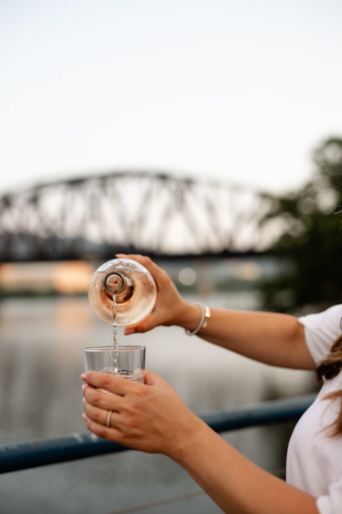 A woman pour wine into a short wine glass.