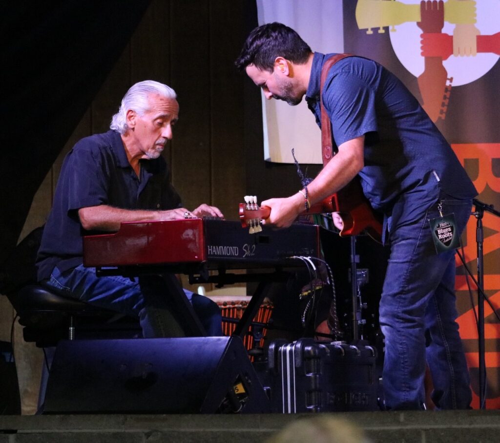 Two women play on a Blues festival stage in Pittsburgh, one on the left on keyboard and one on the right on guitar.