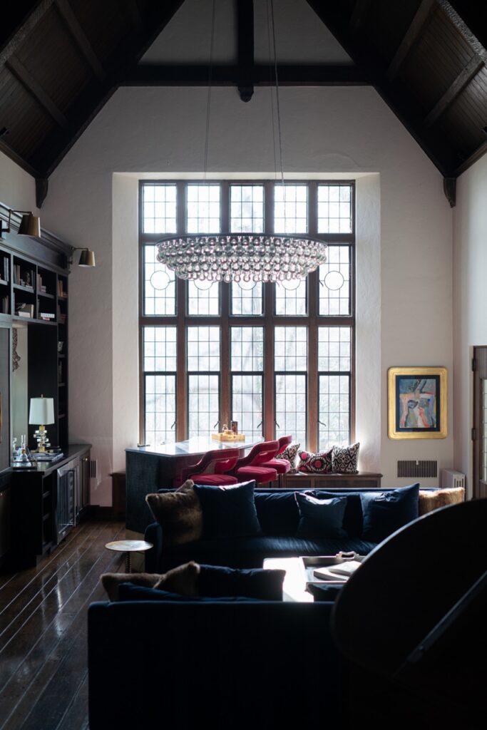 A rectangular window behind a living area with a chandelier hanging from the ceiling.
