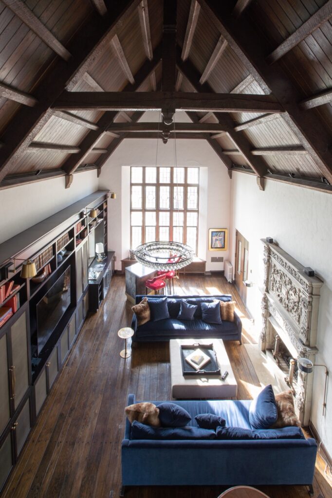 A view from the top of a house with a window in the distance and wood beams in the ceiling.