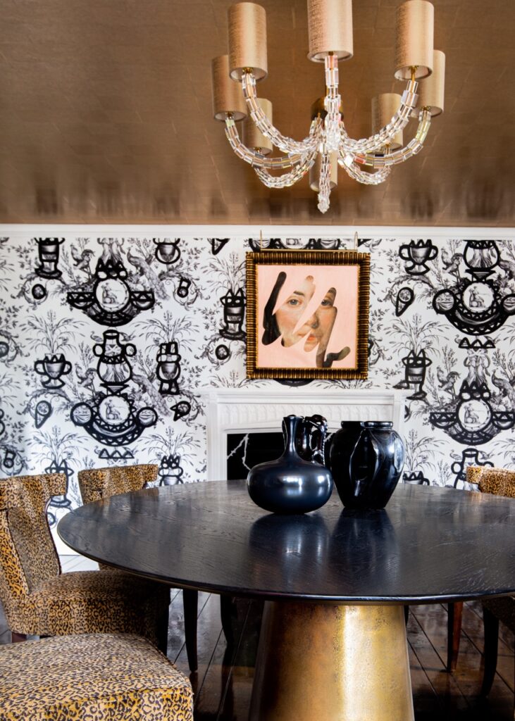 A black table and brown chairs sit in front of a black and white pattern wall.