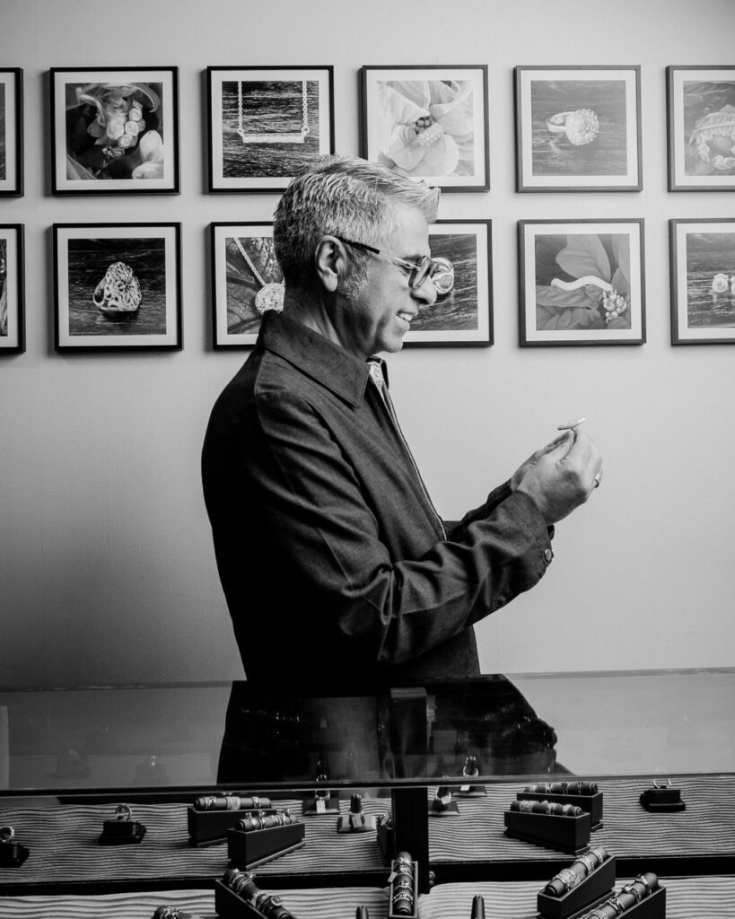 Caesar stands in his designs jewelry shop looking at a case.