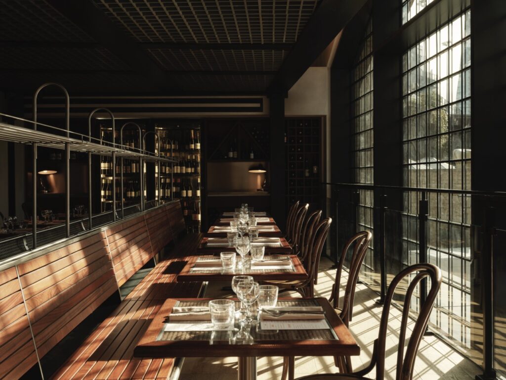 The shun shines through a window onto wood tables and booths inside Cafe Francois in London.