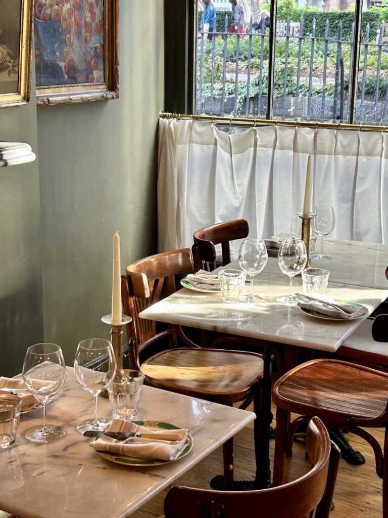 The interior of Cloth in London with two square tables that have candlesticks on them.