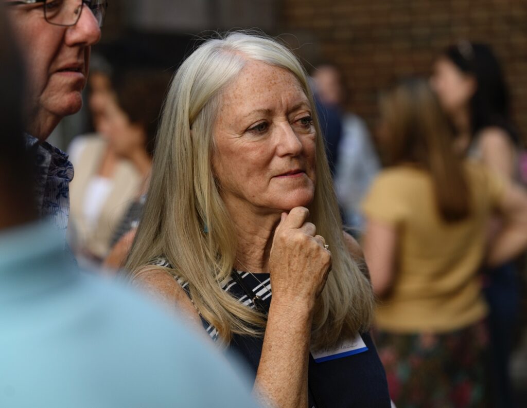 A lady with grey and blonde hair with her hand under her chin.