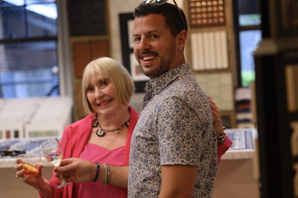 A woman in pink and a man in a pattern button up smile together.