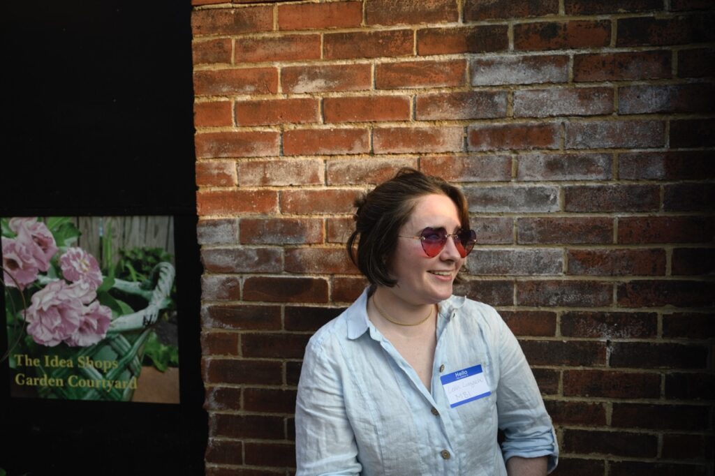 A woman with red heart sunglasses against a brick wall.