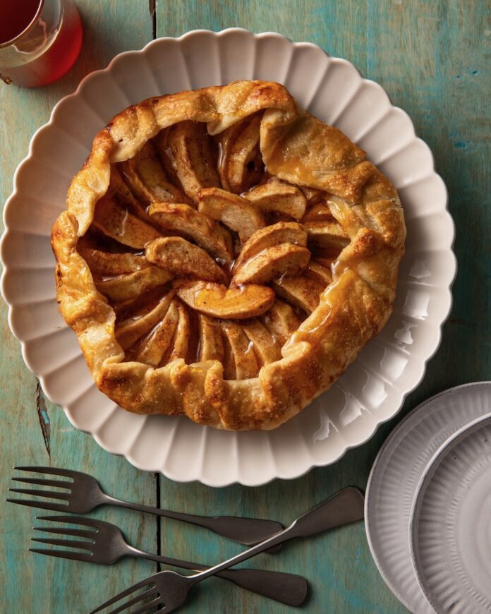 An easy hot honey apple galette sits in a round shape on a white plate with the edges of the galette folded in.