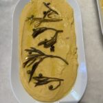 An aerial shot of a Fava Spread, yellow in color, on a white oval dish