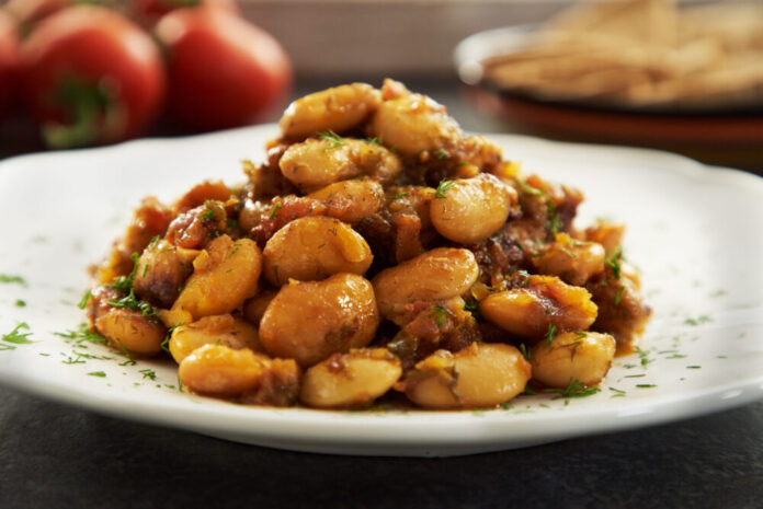 On a white plate sits a mound of GIANT BEANS WITH HONEY AND DILL.