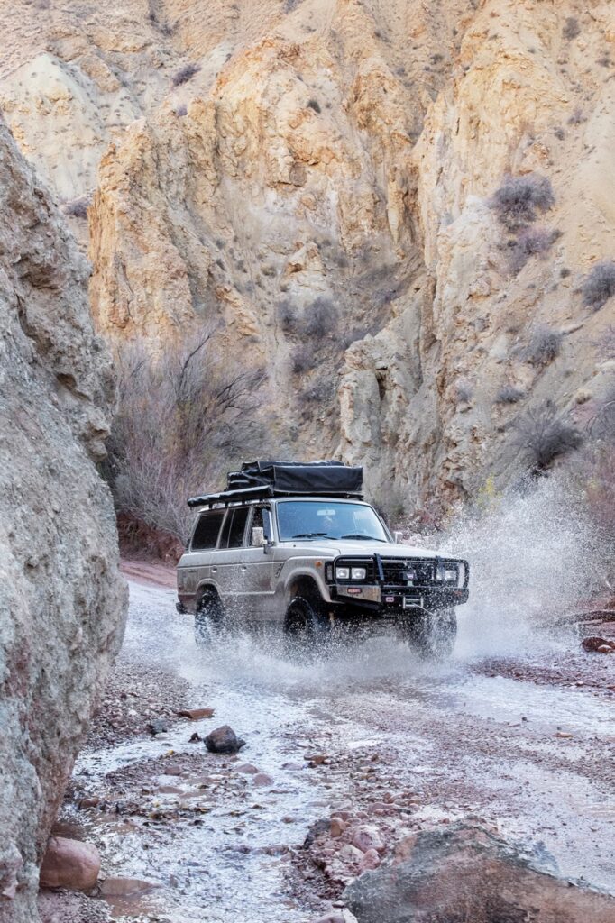 A jeep traveling through water in mountains.