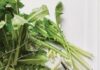 All About Harvesting and Eating Dandelions Dandelion greens sit on a white table beside a pair of clippers.