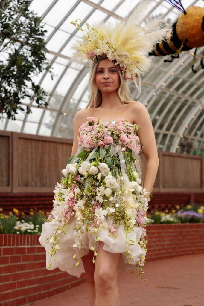 A woman in a flower dress walks down a runway.