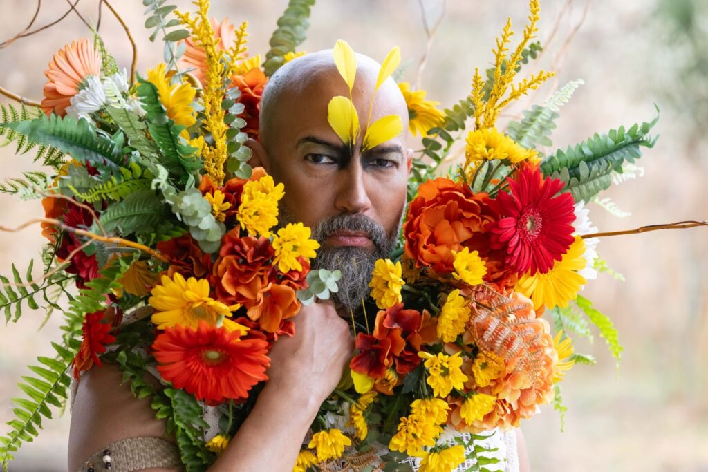 A man with a necklace of flowers around his neck and head.