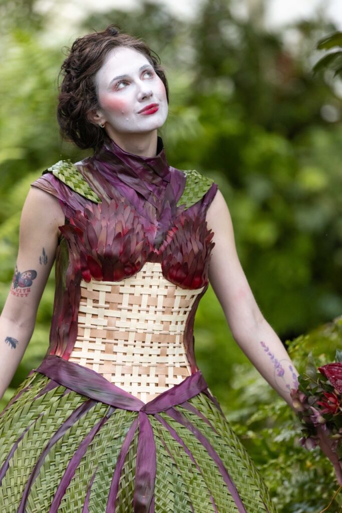 A woman with her face painted white and a greenery dress.