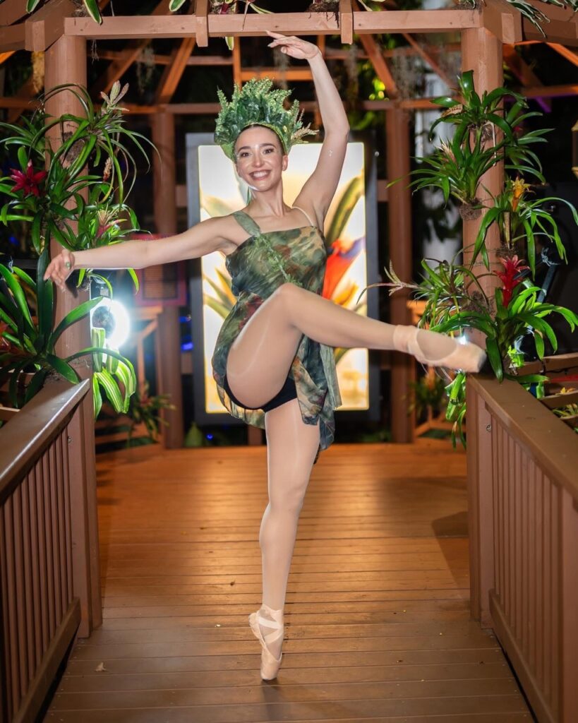 A dancer in a green flower crown lifts her leg.