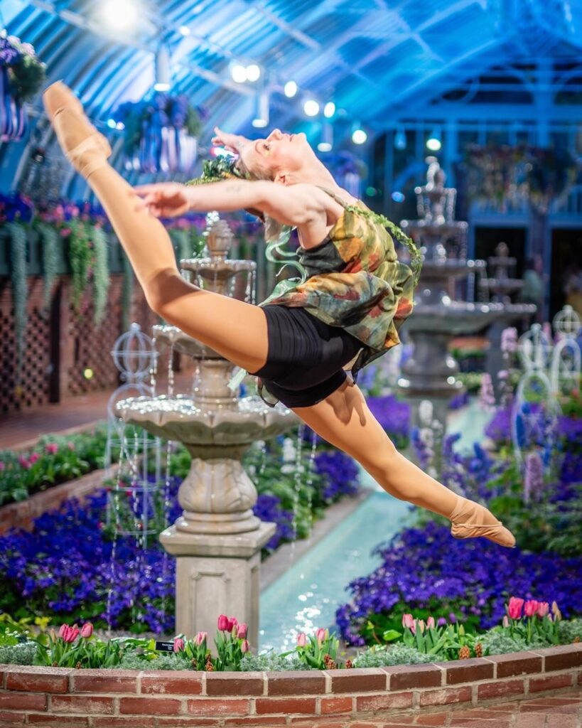 A dancer leaps through the air at phipps gardens.