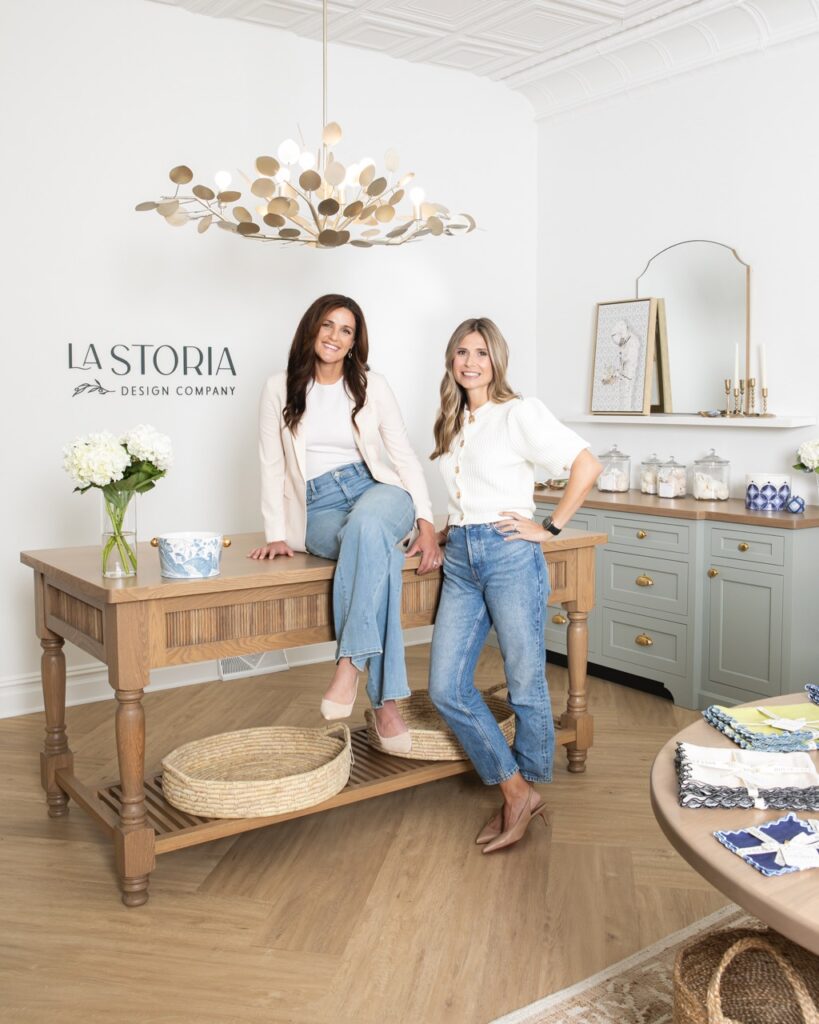 Two women in white lean and sit on the La Storia counter.