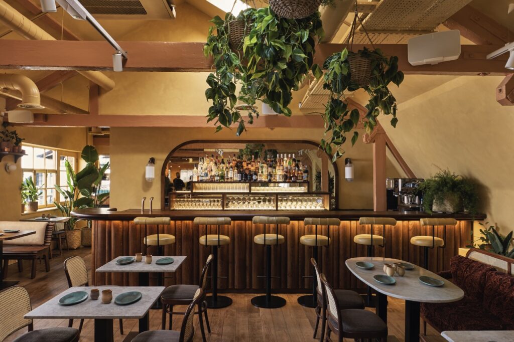 The dining room at Darjeeling Express with neutral walls and greenery on the ceiling located in London.
