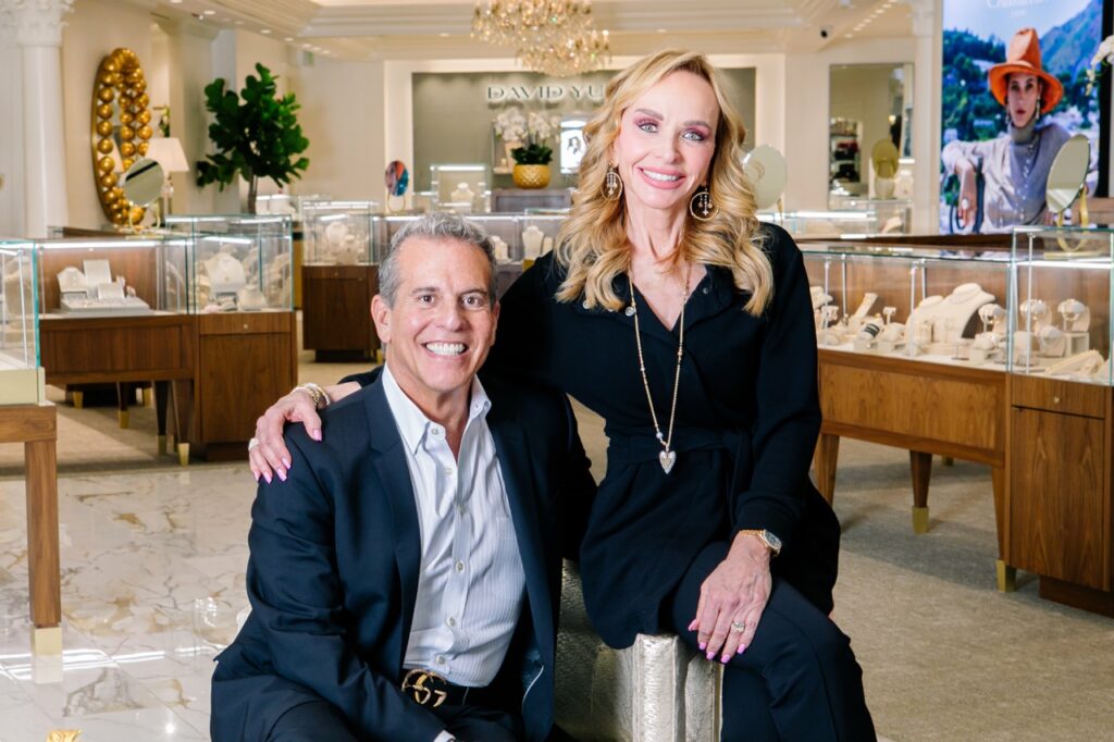 A woman in a black pantsuit and a man in a suit sit side by side.