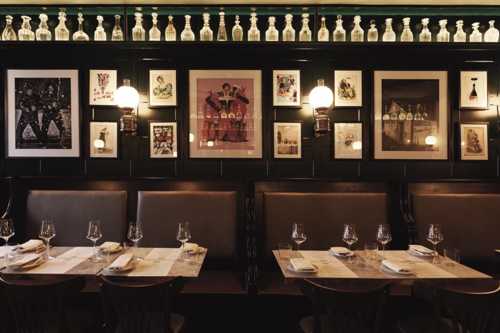 The inside dark booth lounge at Noble Rot in London with framed photos on the wall.