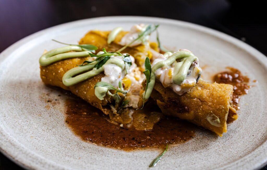 A street corn taquito cut in two to show the filling.