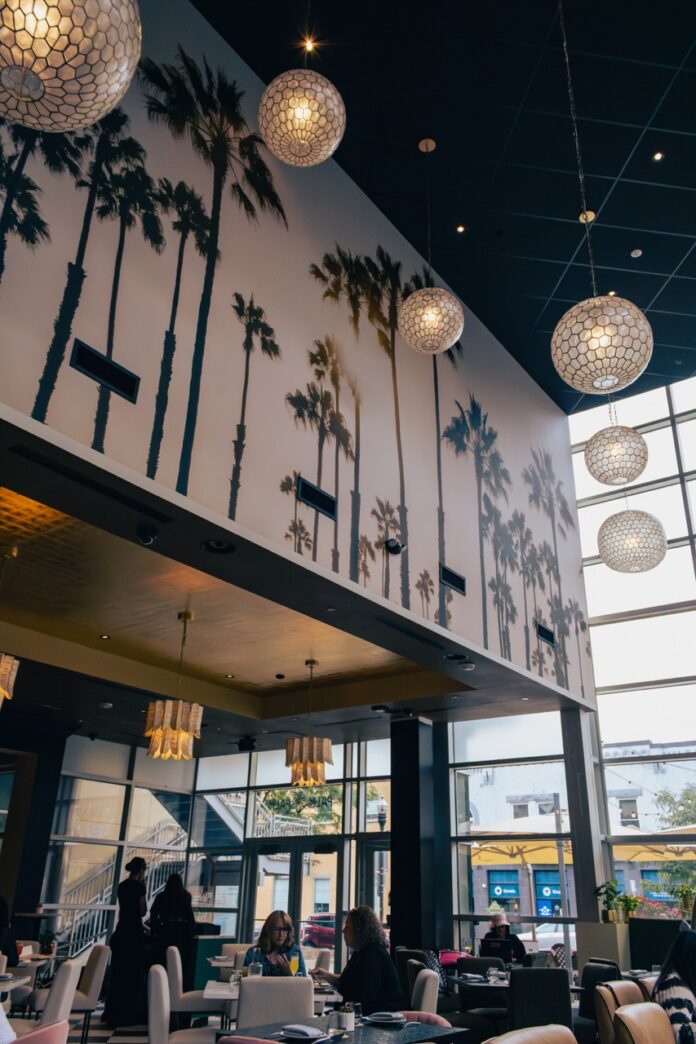 A wall of palm tree art with glowing orb lights hanging from the ceiling of the Palm Palm dining room.