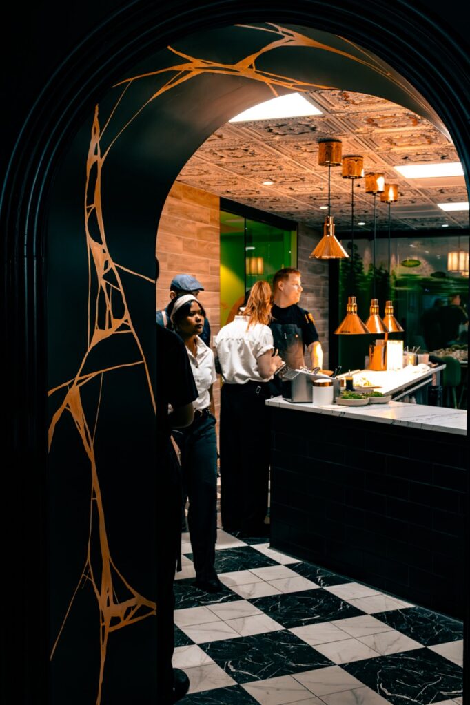 An arch doorway with gold embellishments that looks into the kitchen.