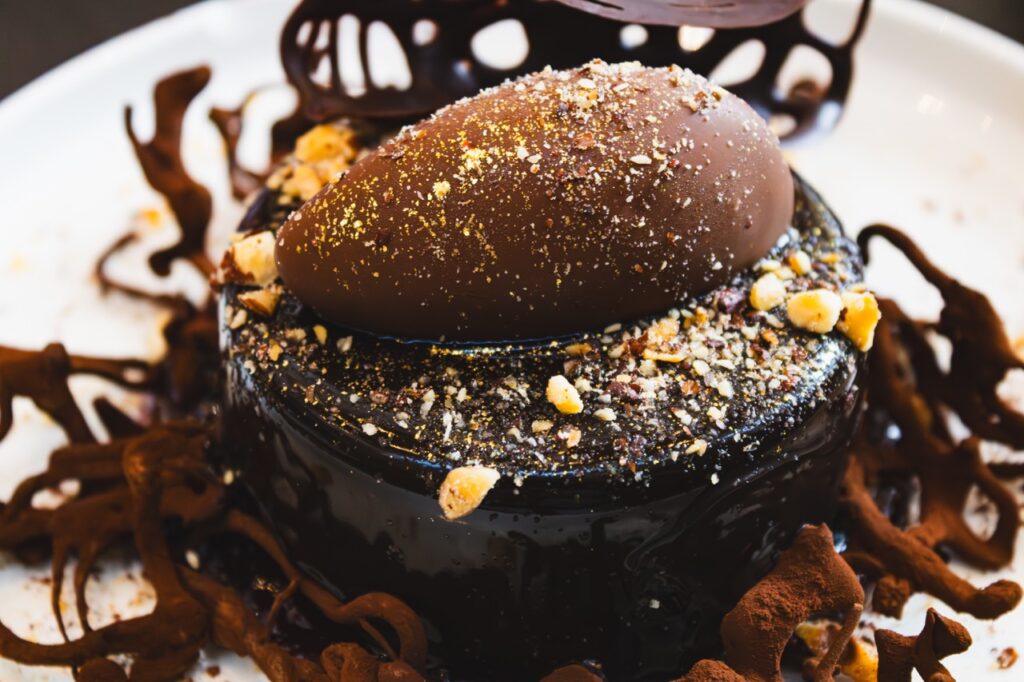 A chocolate dessert with a ganache cake, mouse, and nuts.