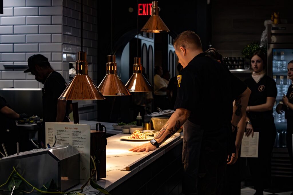 A chef looks over a dish in front of him in the Palm Palm kitche.