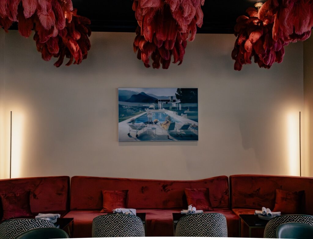 Palm Palm's red lounge area with a long couch, chairs and frills over top.