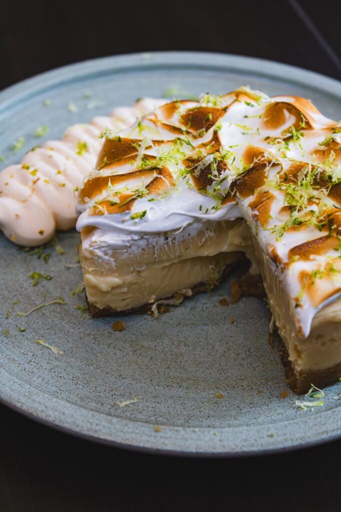 A Key Lime Pie with a slice taken out of it and torched meringue on top.