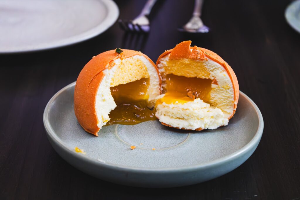 A split open orange dessert with orange jelly flowing out.