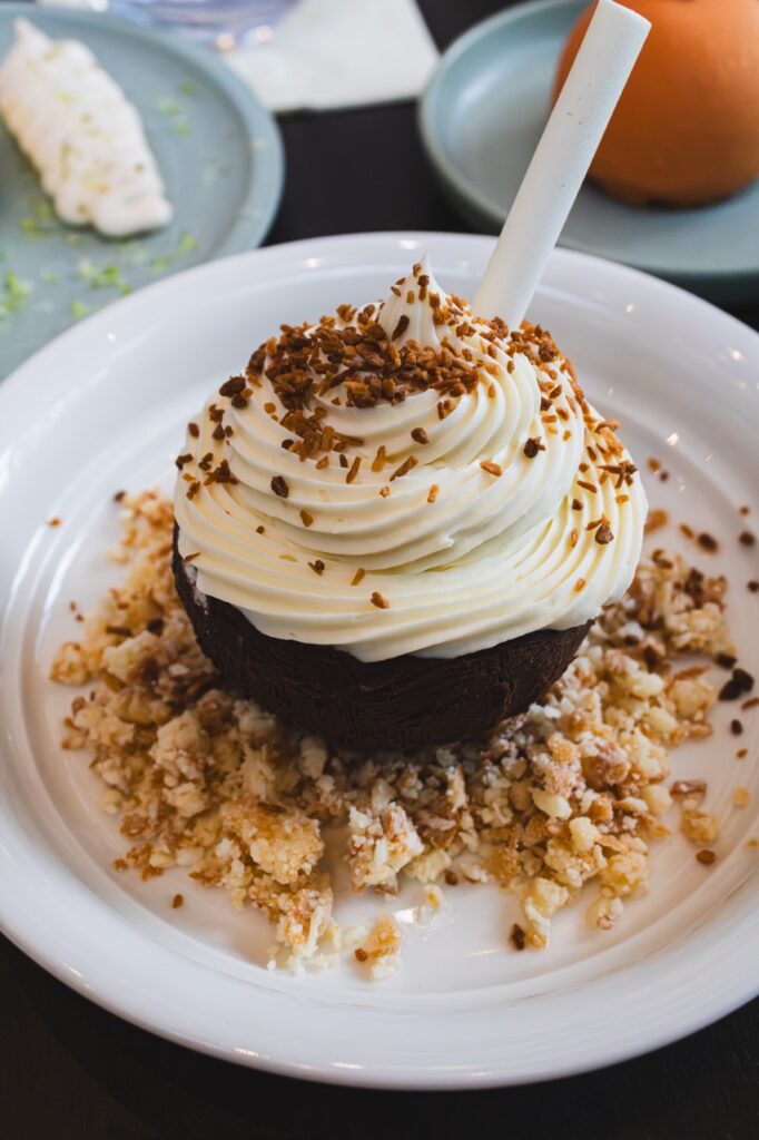 A coconut cupcake wit crunchies on the whipped cream.