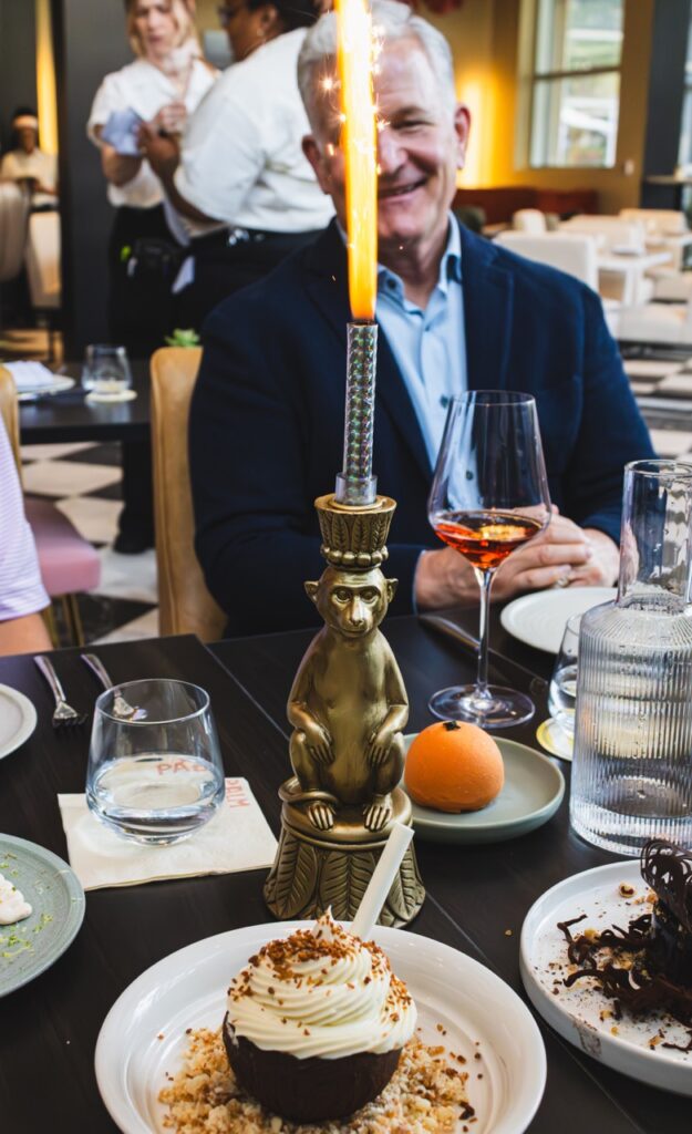 A man laughs behind a large flare firework surrounded by dessert plates.
