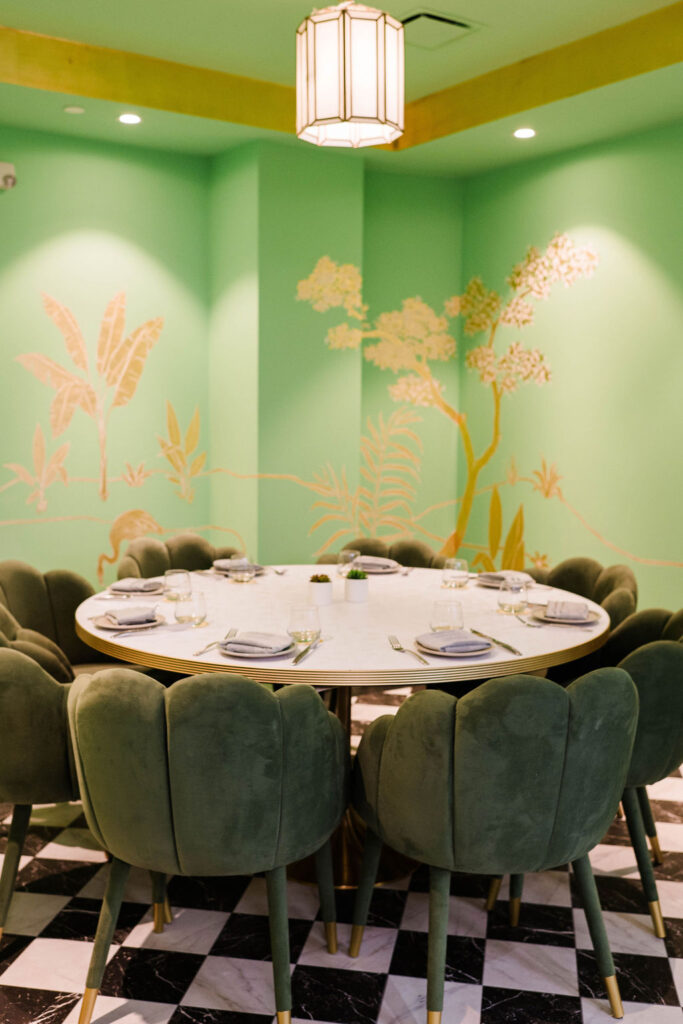 A green and gold embellished private dining room with green velvet chairs at Palm Palm.